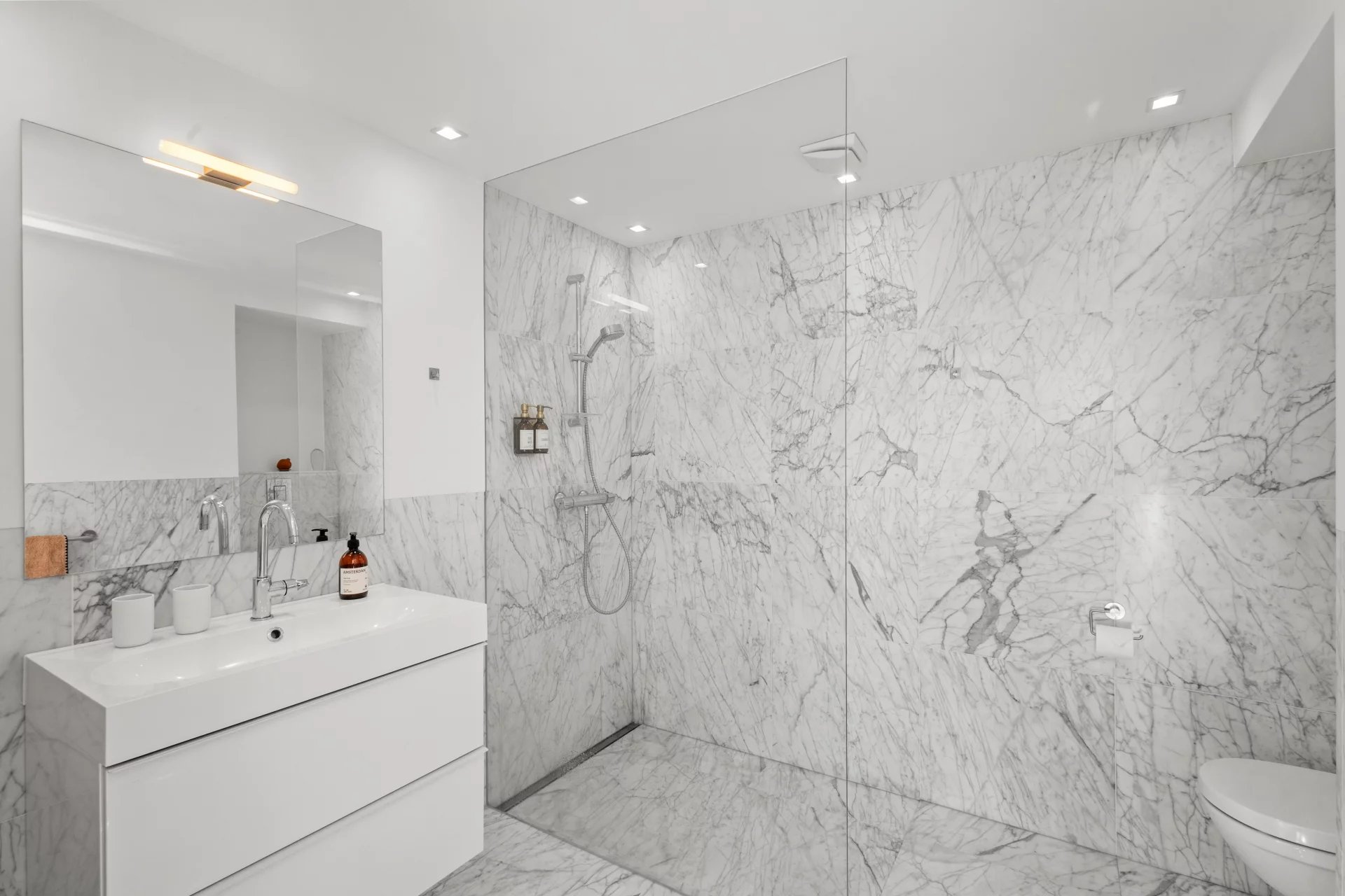Modern bathroom with marble shower and vanity unit.