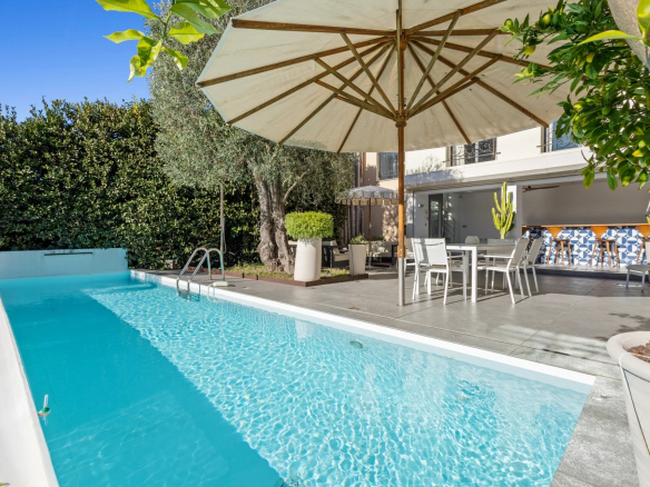 Swimming pool and terrace of a private mansion in Le Cannet with parasol and garden furniture.