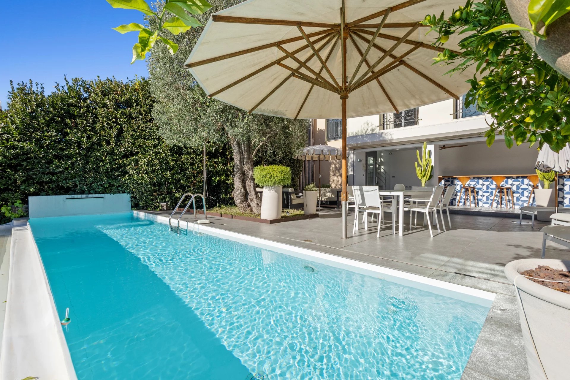 Swimming pool and terrace of a private mansion in Le Cannet with parasol and garden furniture.