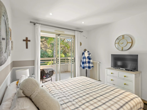 Chambre d'un appartement avec lit double, balcon et télévision.