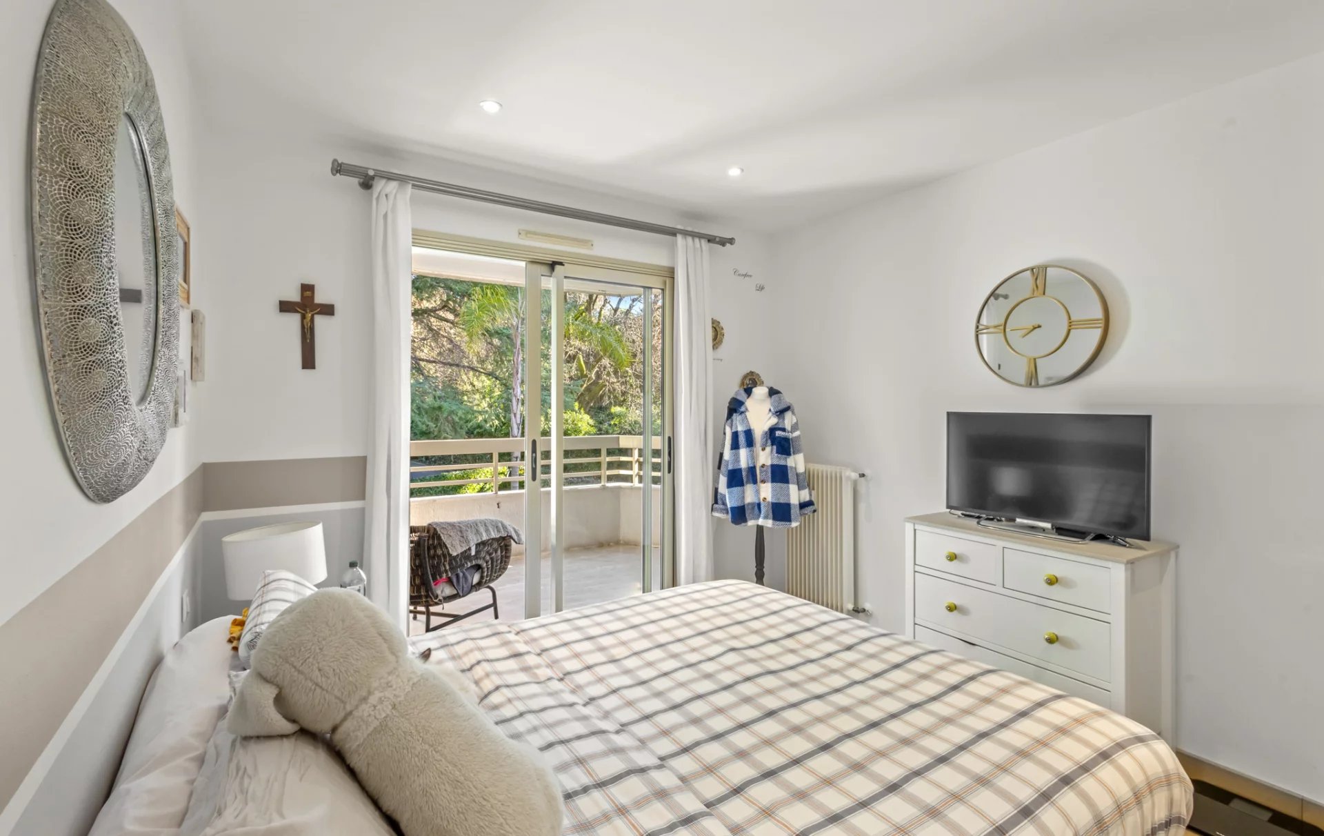 Chambre d'un appartement avec lit double, balcon et télévision.