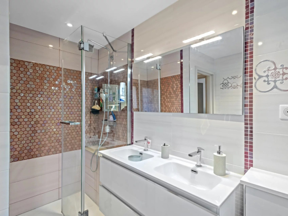 Salle de douche moderne avec douche en verre et carrelage hexagonal.