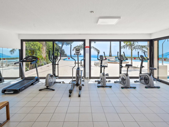 Salle de sport moderne avec équipements de fitness et vue sur la mer.