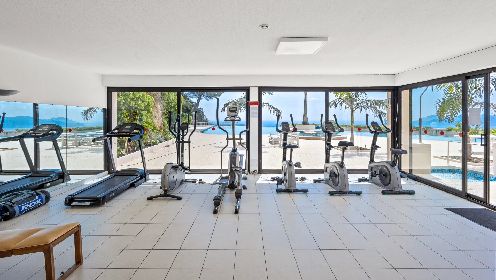 Salle de sport moderne avec équipements de fitness et vue sur la mer.