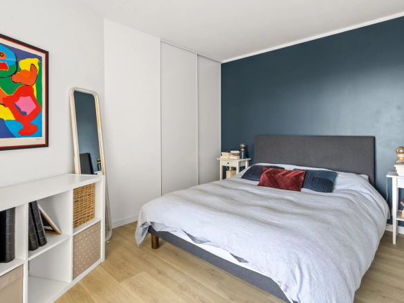 Chambre d'un appartement moderne avec lit double et décoration colorée.