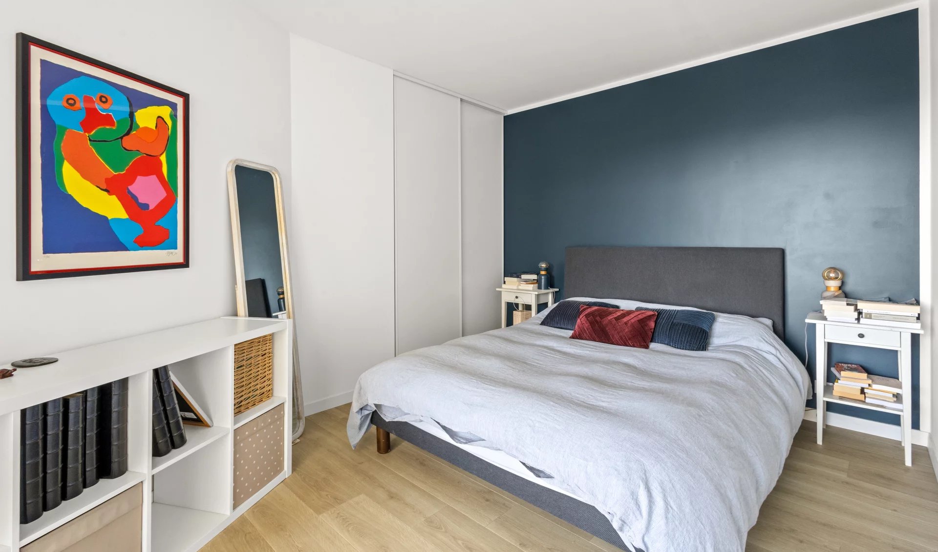 Chambre d'un appartement moderne avec lit double et décoration colorée.