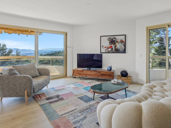 Salon lumineux d'un appartement 3 pièces avec vue sur la mer, mobilier moderne et baies vitrées.
