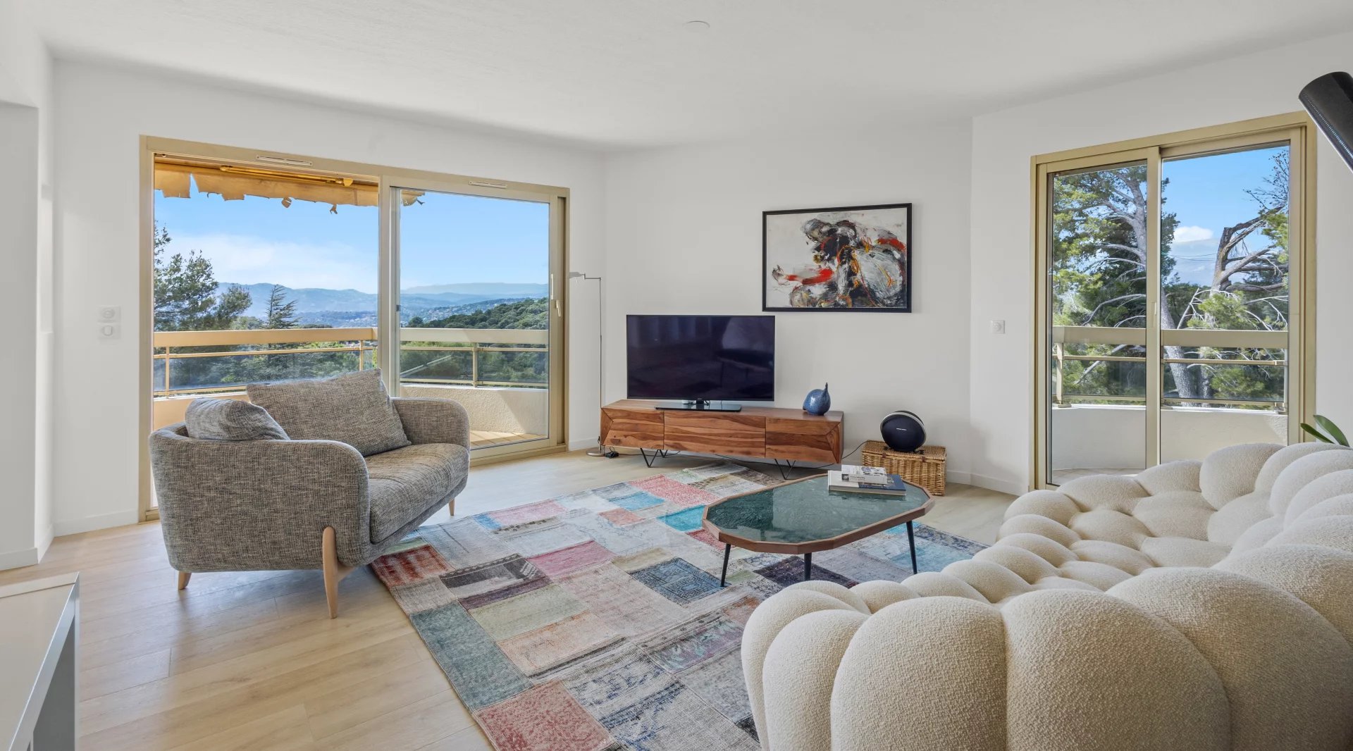 Salon lumineux d'un appartement 3 pièces avec vue sur la mer, mobilier moderne et baies vitrées.