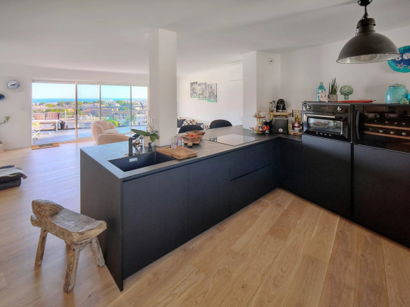 Interior of a modern apartment with open kitchen and sea view.
