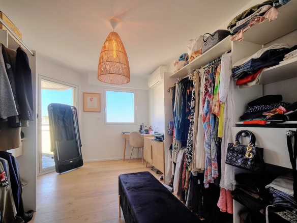 Spacious dressing room with clothes and accessories, windows and natural light.