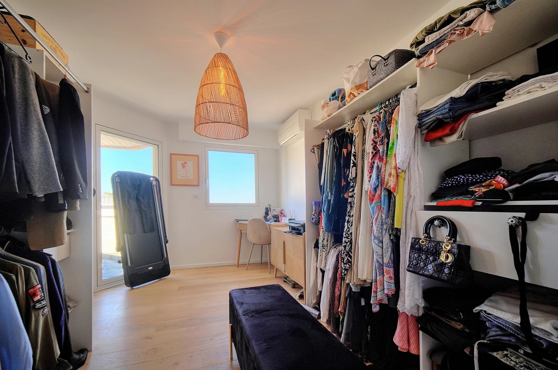 Spacious dressing room with clothes and accessories, windows and natural light.