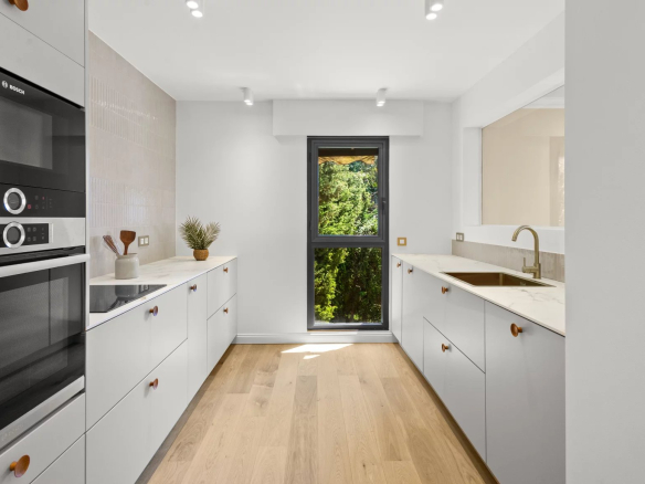 Modern kitchen with integrated appliances and a window overlooking the outside.
