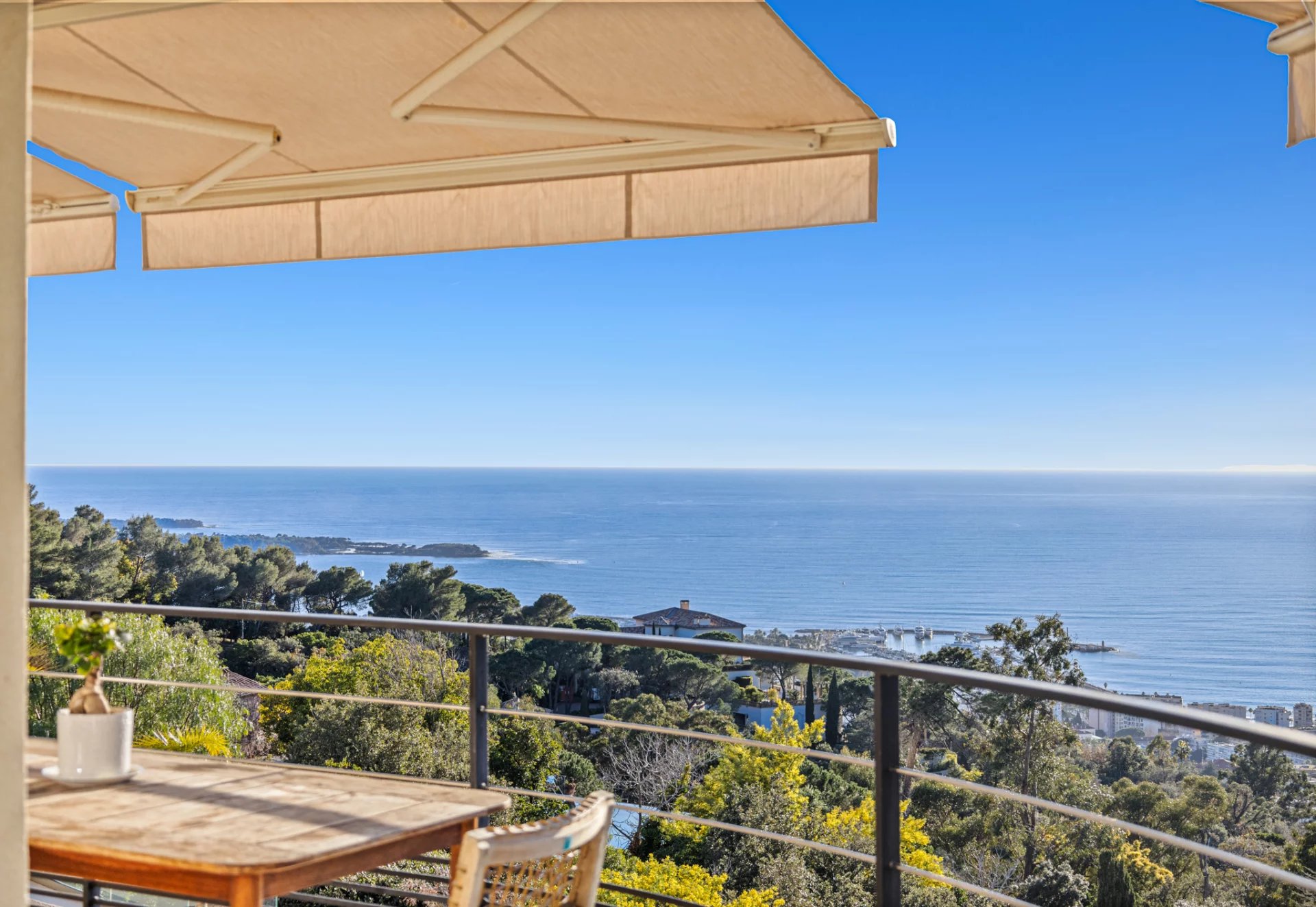 Vue mer panoramique depuis un appartement à Cannes Vue panoramique sur la mer depuis un balcon avec une table en bois et des parasols.