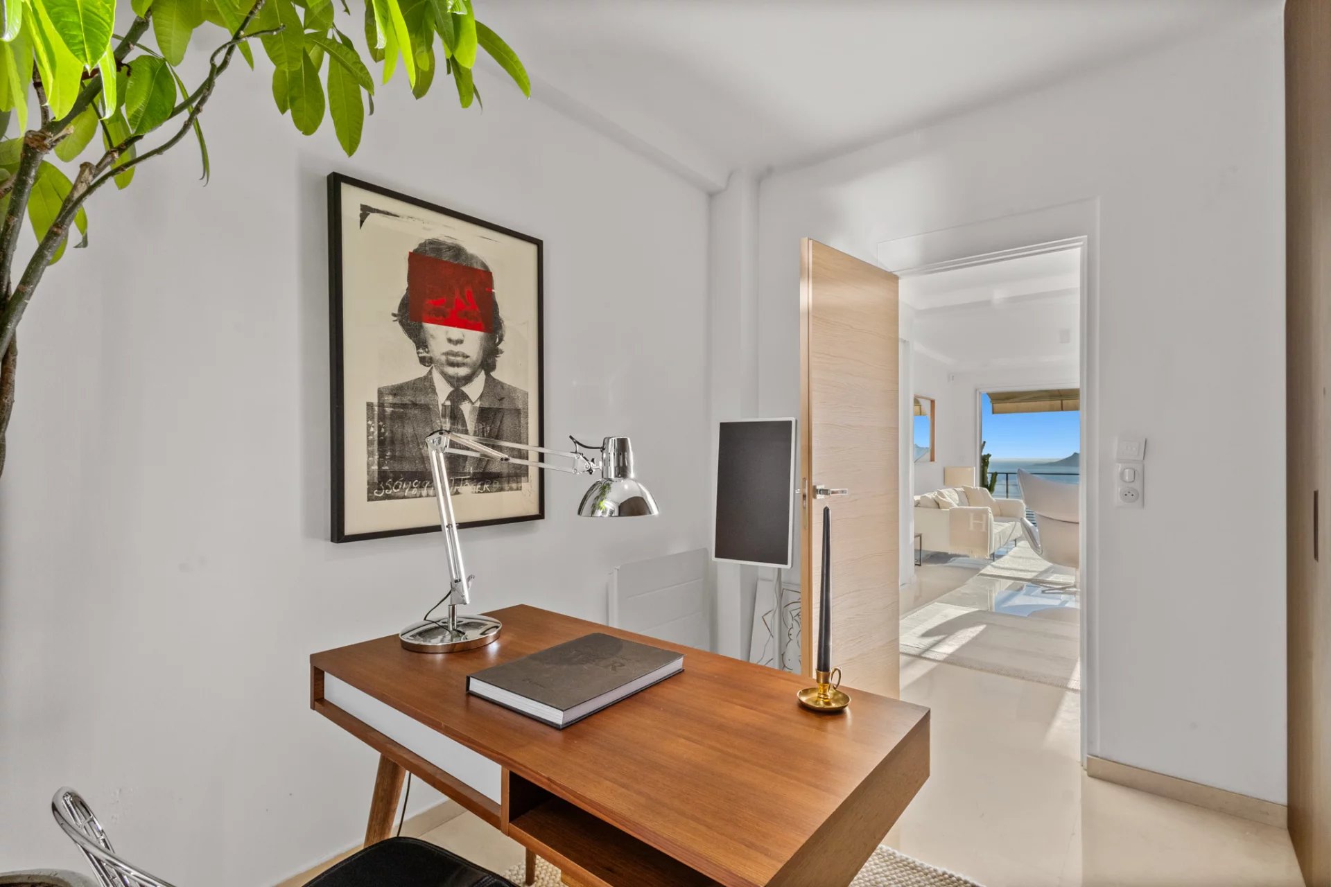 Bureau avec vue à Cannes Bureau moderne avec une œuvre d'art au mur et une vue sur l'extérieur à Cannes.