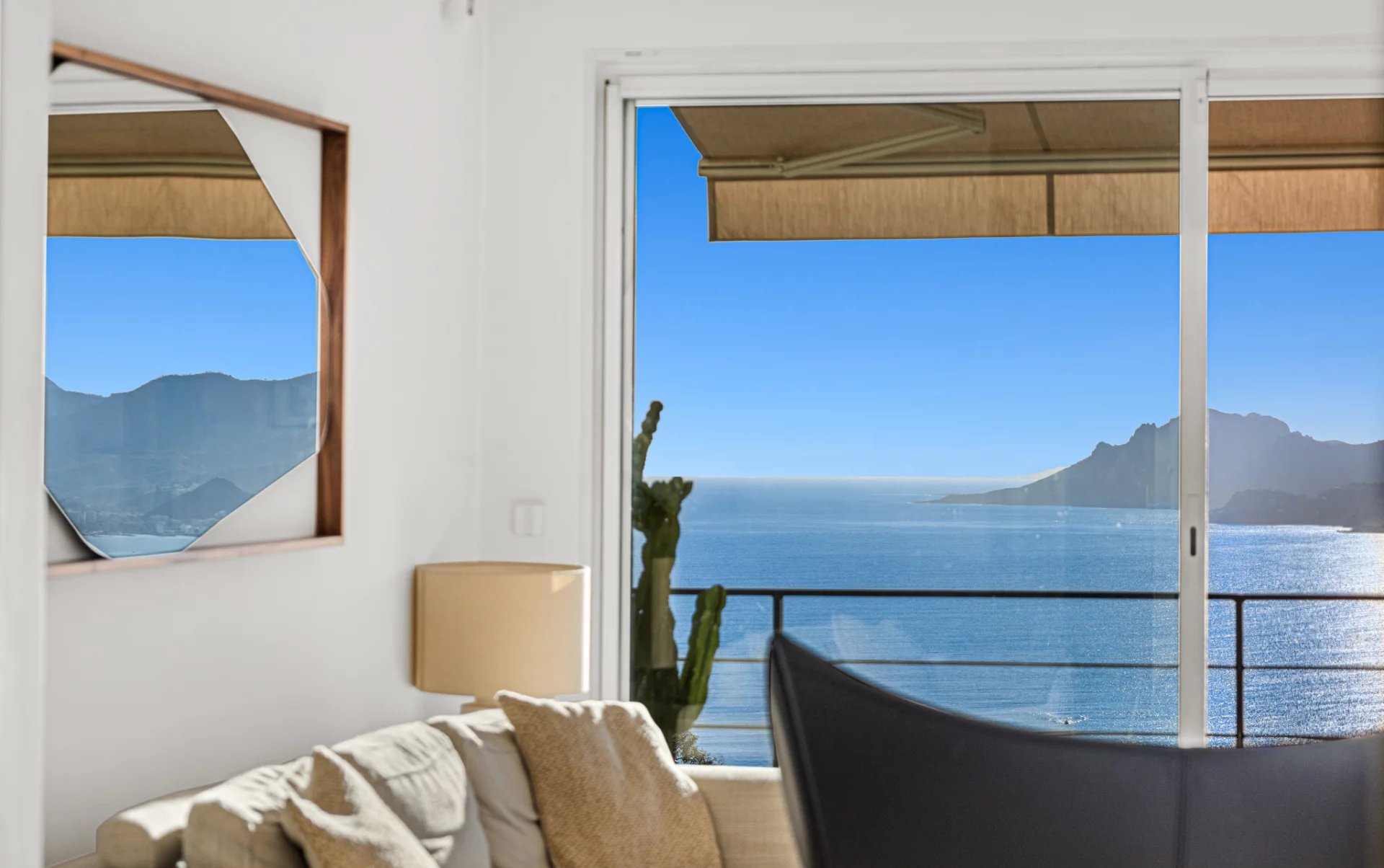 Vue mer depuis un appartement à Cannes Vue panoramique sur la mer depuis un appartement à Cannes, avec un canapé et des montagnes en arrière-plan.