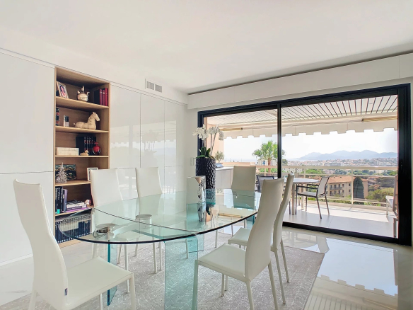 Intérieur d'un appartement rénové avec une grande table en verre et vue sur le paysage.