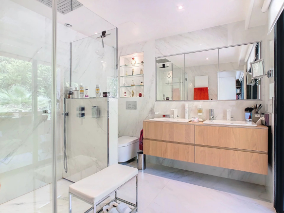 Salle de bain moderne avec douche en verre et meuble vasque en bois.
