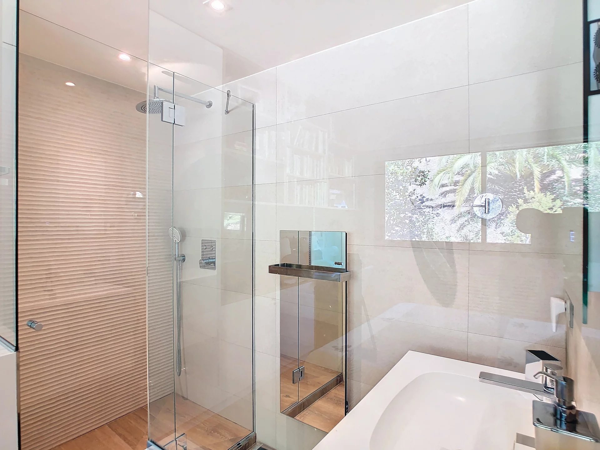 Salle de bain moderne avec douche en verre et baignoire, éclairage naturel.