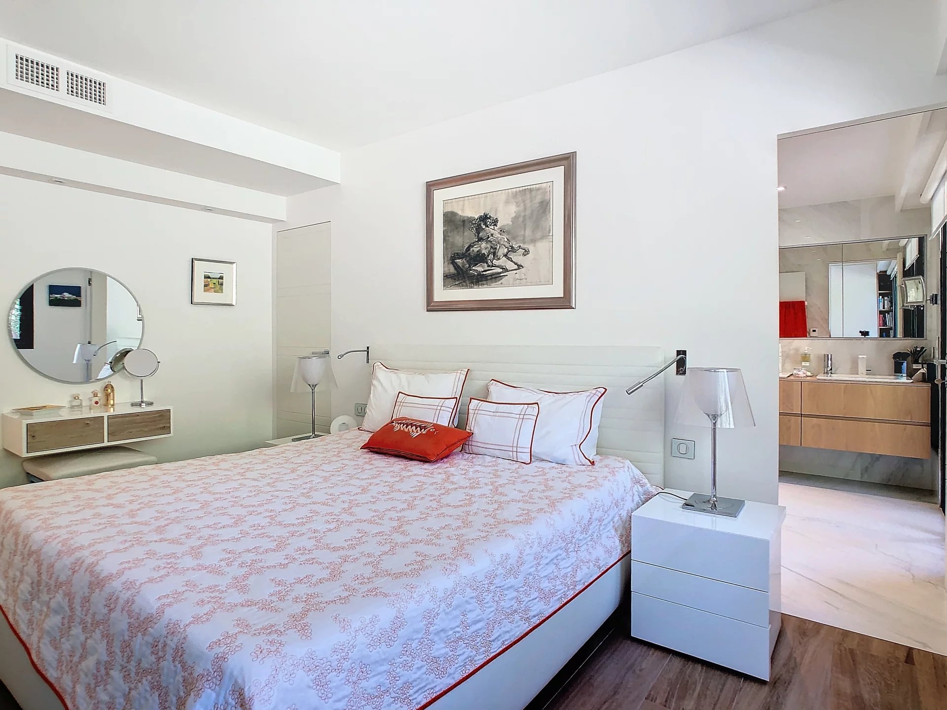 Chambre d'un appartement rénové avec lit double et salle de bain visible en arrière-plan.