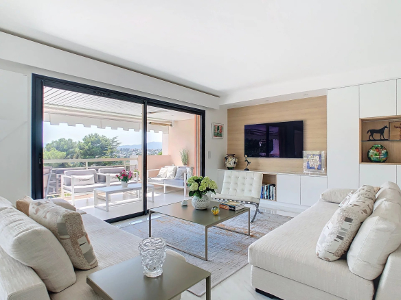 Salon lumineux d'un appartement rénové avec vue, mobilier moderne et accès à une terrasse.