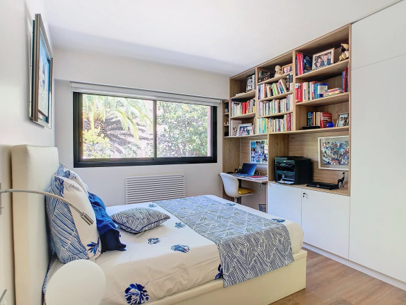 Chambre d'un appartement rénové avec lit, bureau et étagères à Le Cannet.