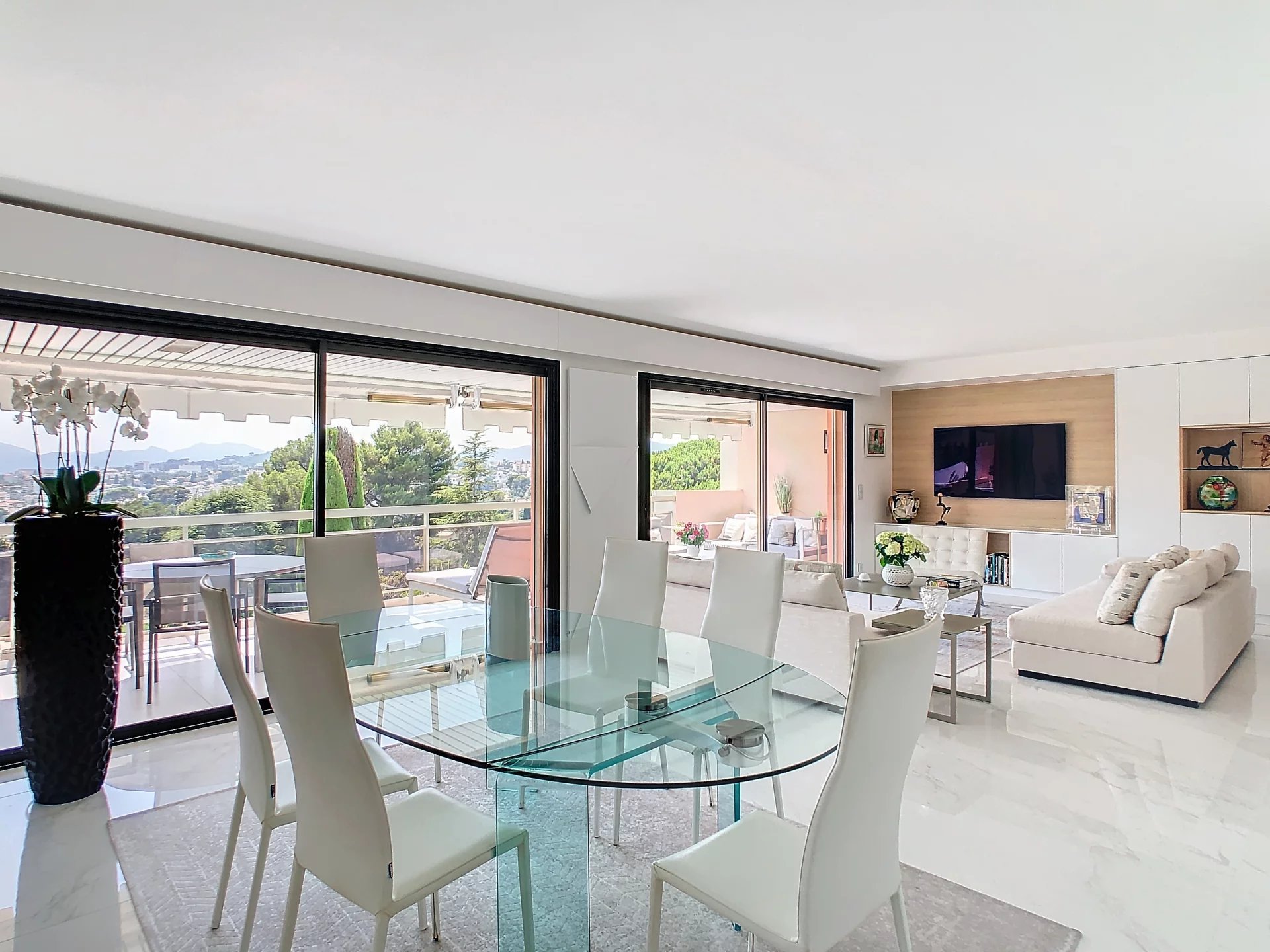 Intérieur d'un appartement rénové avec salle à manger en verre et salon lumineux.