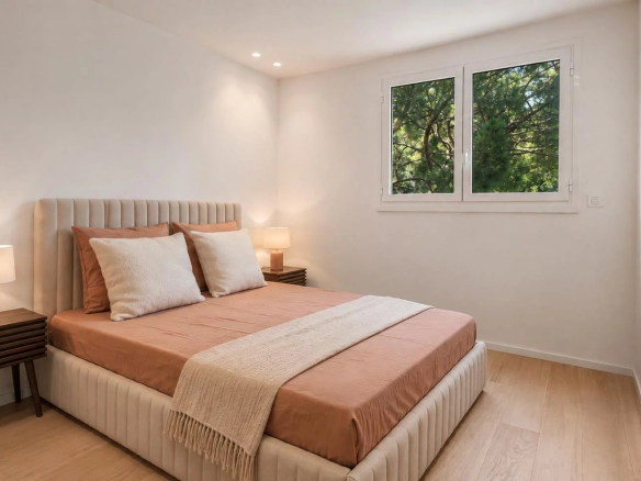 Chambre d'un appartement rénové avec lit double et fenêtres laissant entrer la lumière.