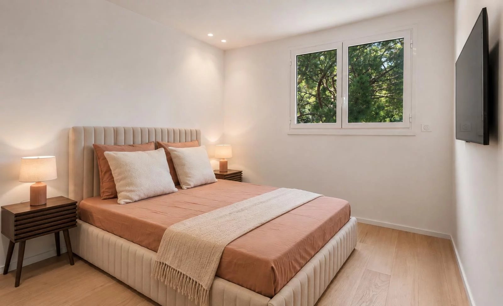 Chambre d'un appartement rénové avec lit double et fenêtres laissant entrer la lumière.