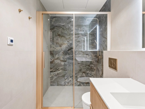 Salle de bain moderne avec douche en verre et murs en marbre