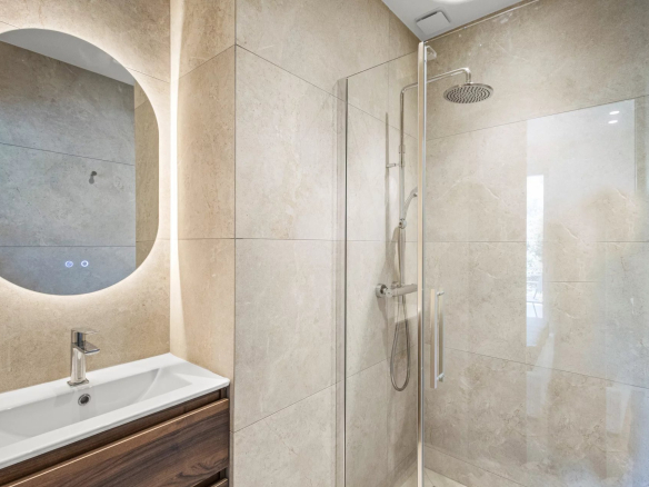 Salle de bain moderne avec douche en verre et lavabo dans un appartement rénové.
