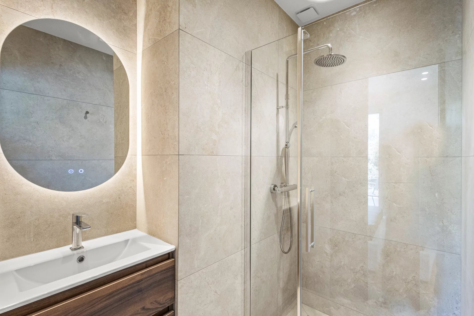 Salle de bain moderne avec douche en verre et lavabo dans un appartement rénové.