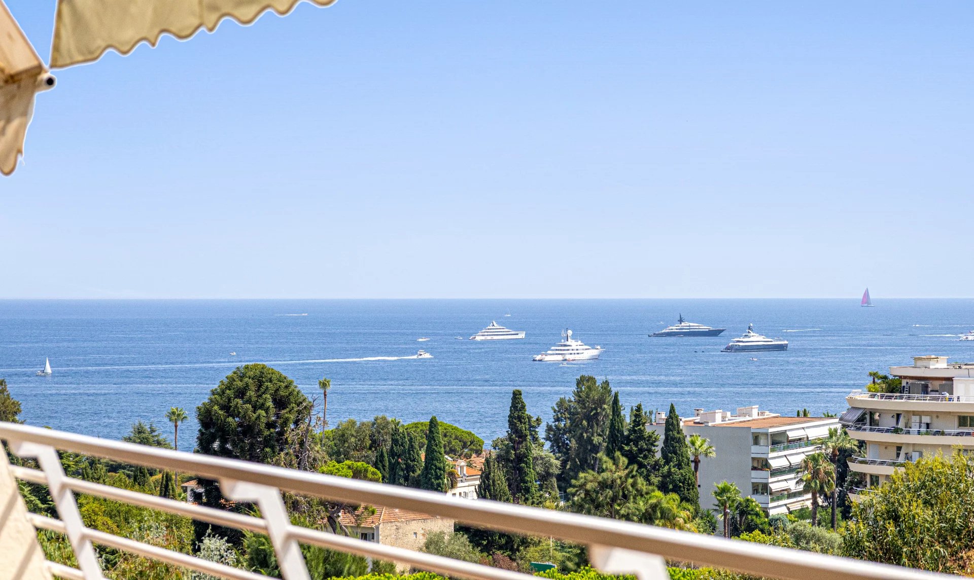 Vue panoramique sur la mer depuis un balcon d'appartement à Cannes, avec des yachts au large.