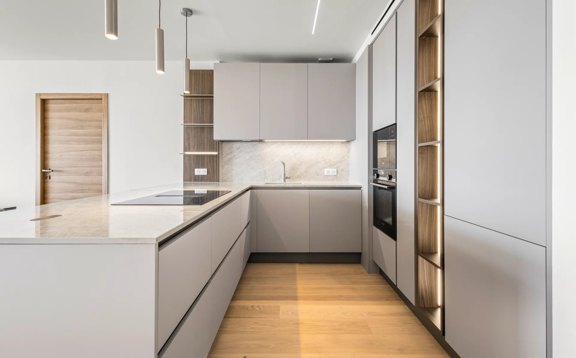Cuisine moderne et rénovée d'un appartement à Cannes avec des meubles en bois et des appareils intégrés.