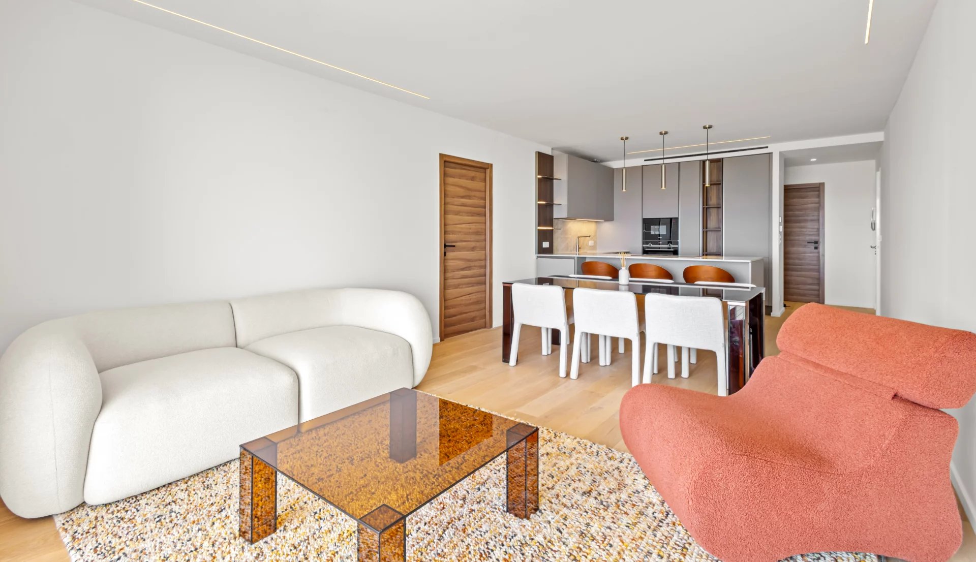 Intérieur d'un appartement rénové avec salon moderne, table à manger et cuisine ouverte.