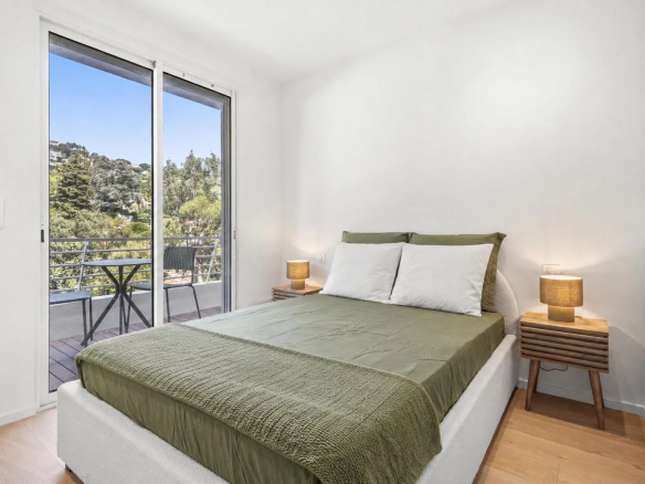 Chambre d'un appartement rénové à Cannes avec balcon et vue sur la nature.