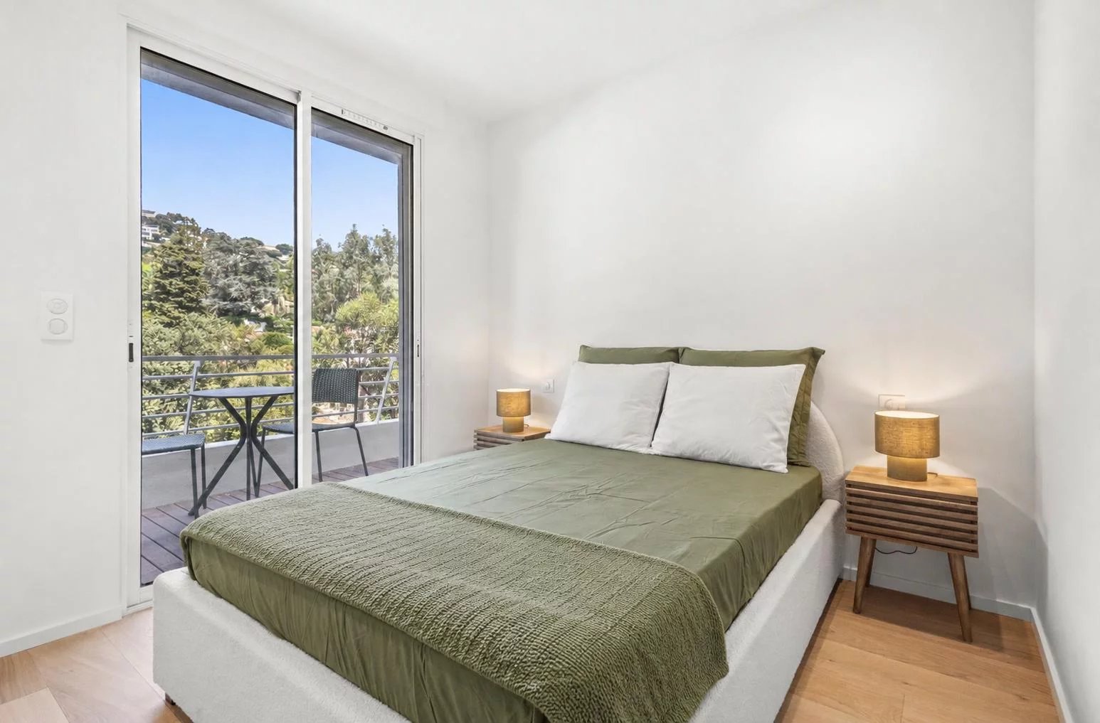 Chambre d'un appartement rénové à Cannes avec balcon et vue sur la nature.