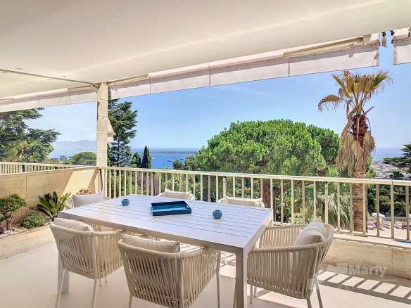 Terrace of an apartment in Cannes with views of the sea and trees.