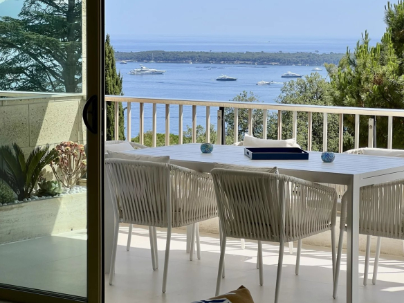 Apartment terrace with sea view in Cannes, white outdoor furniture.