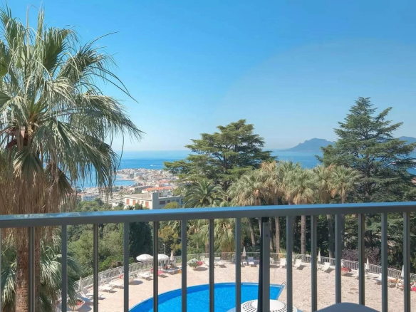 View from a terrace with swimming pool and palm trees, overlooking the sea in Cannes.