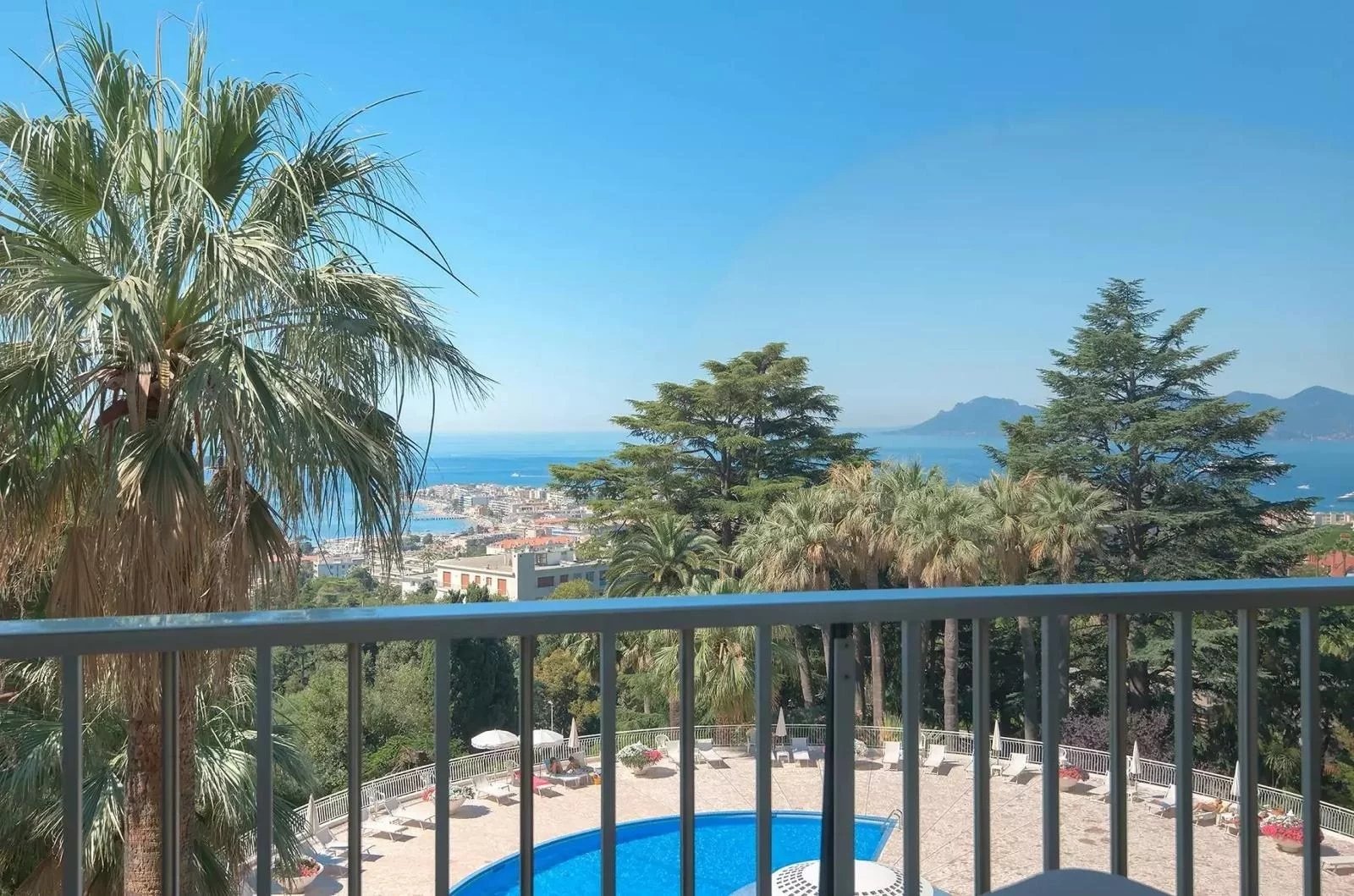 Sea view from a residence in Cannes View from a terrace with swimming pool and palm trees, overlooking the sea in Cannes.