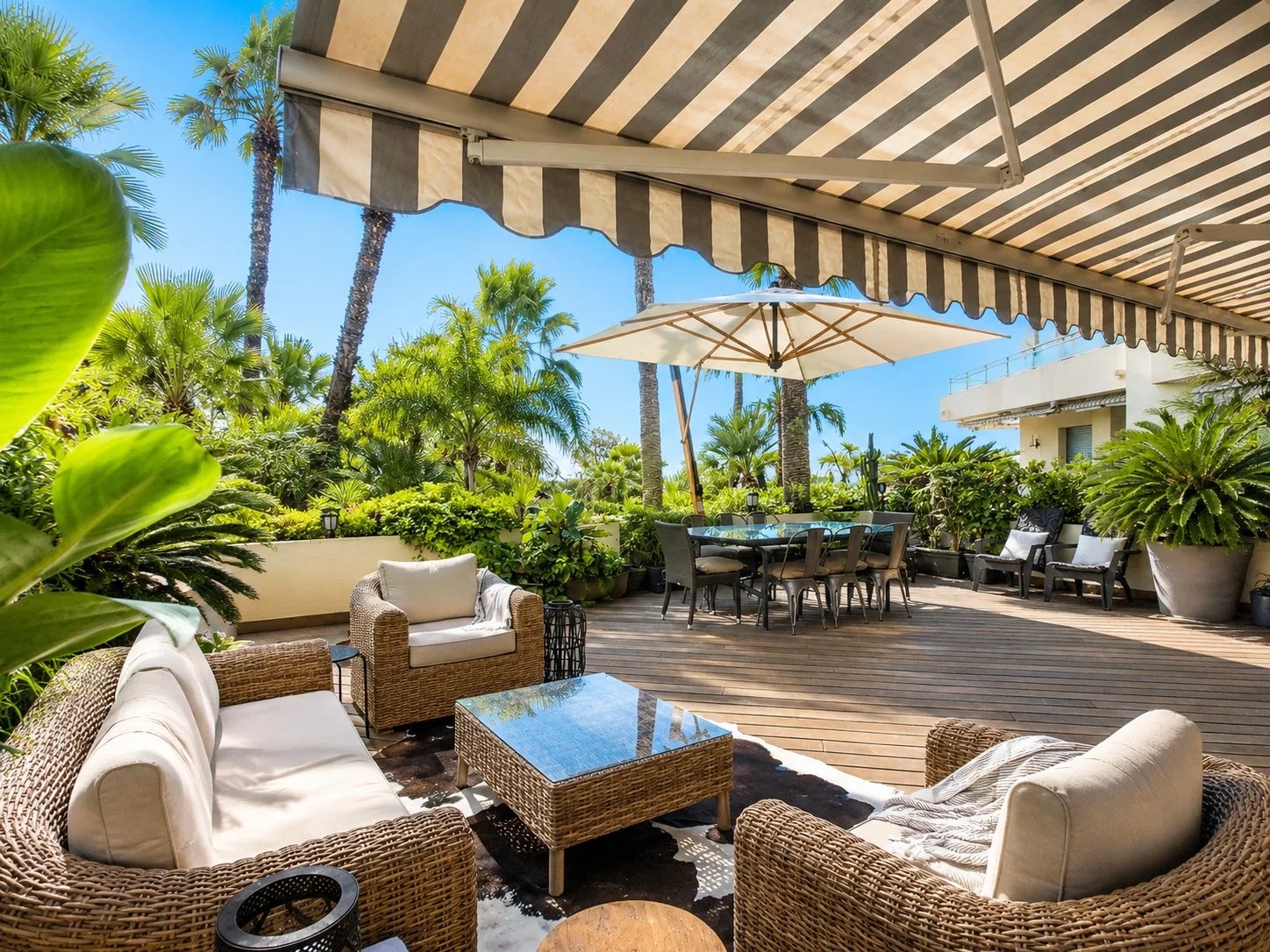 Spacious terrace with garden furniture, surrounded by greenery and palm trees in Cannes.