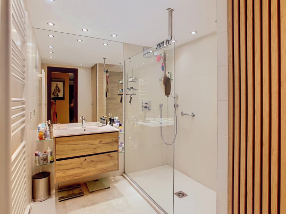 Modern bathroom with walk-in shower and wooden vanity.