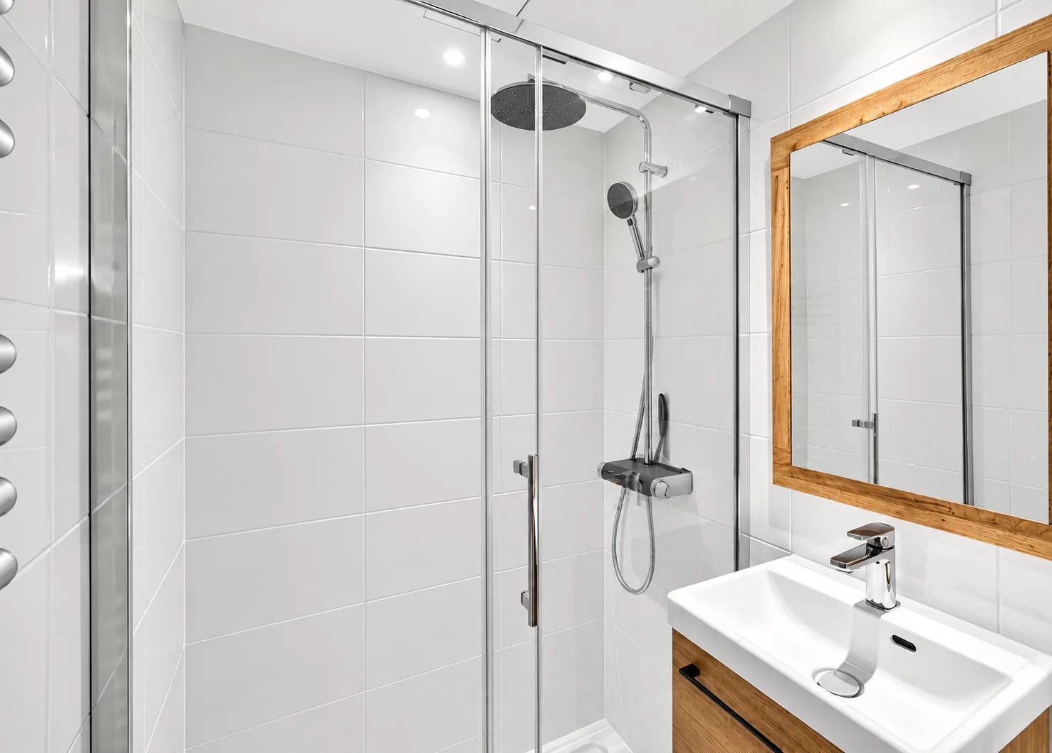 Modern bathroom with walk-in shower and wooden vanity unit.