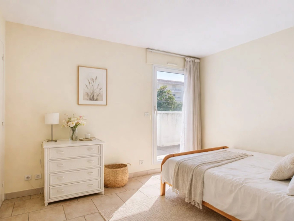 Chambre lumineuse avec lit simple et accès à un balcon, dans une maison de ville à Cannes.