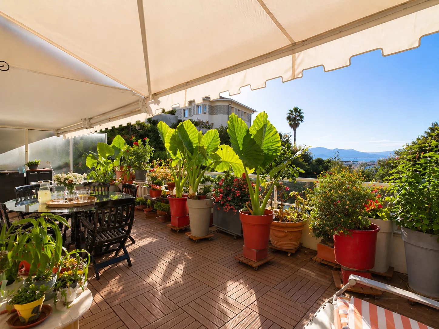 Terrasse avec vue mer à Cannes Terrasse d'un appartement à Cannes avec plantes et mobilier de jardin, vue dégagée sur la mer.