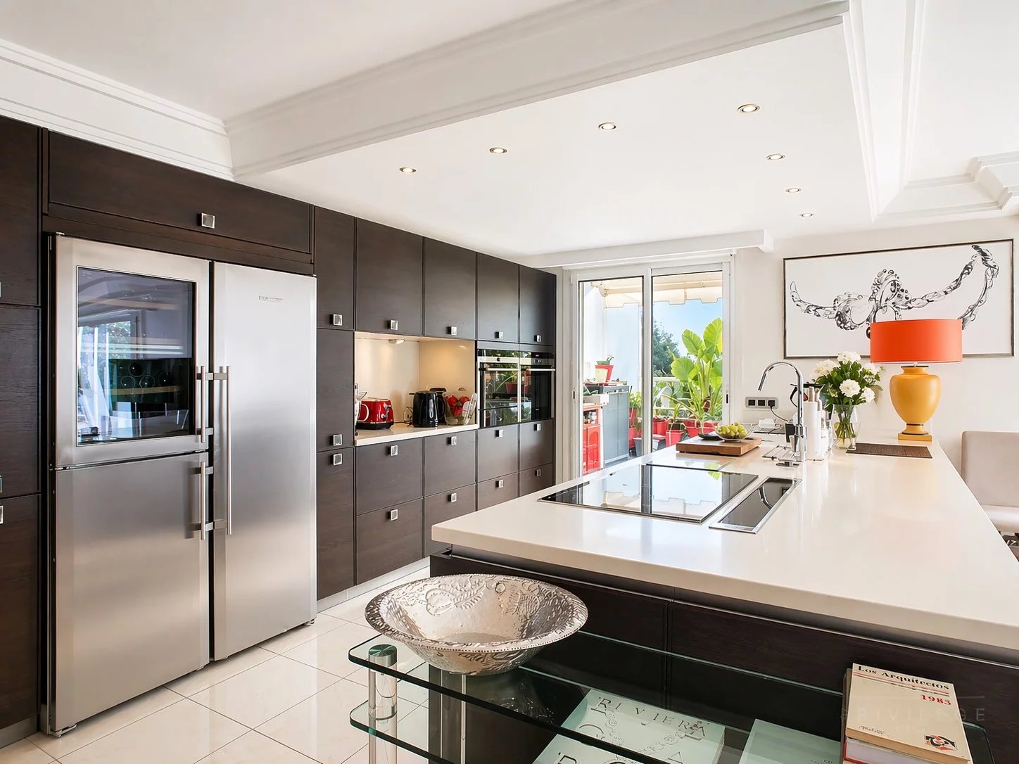 Cuisine d’un appartement d’exception à Cannes Cuisine moderne et équipée d'un appartement à Cannes avec îlot central et électroménagers en inox.
