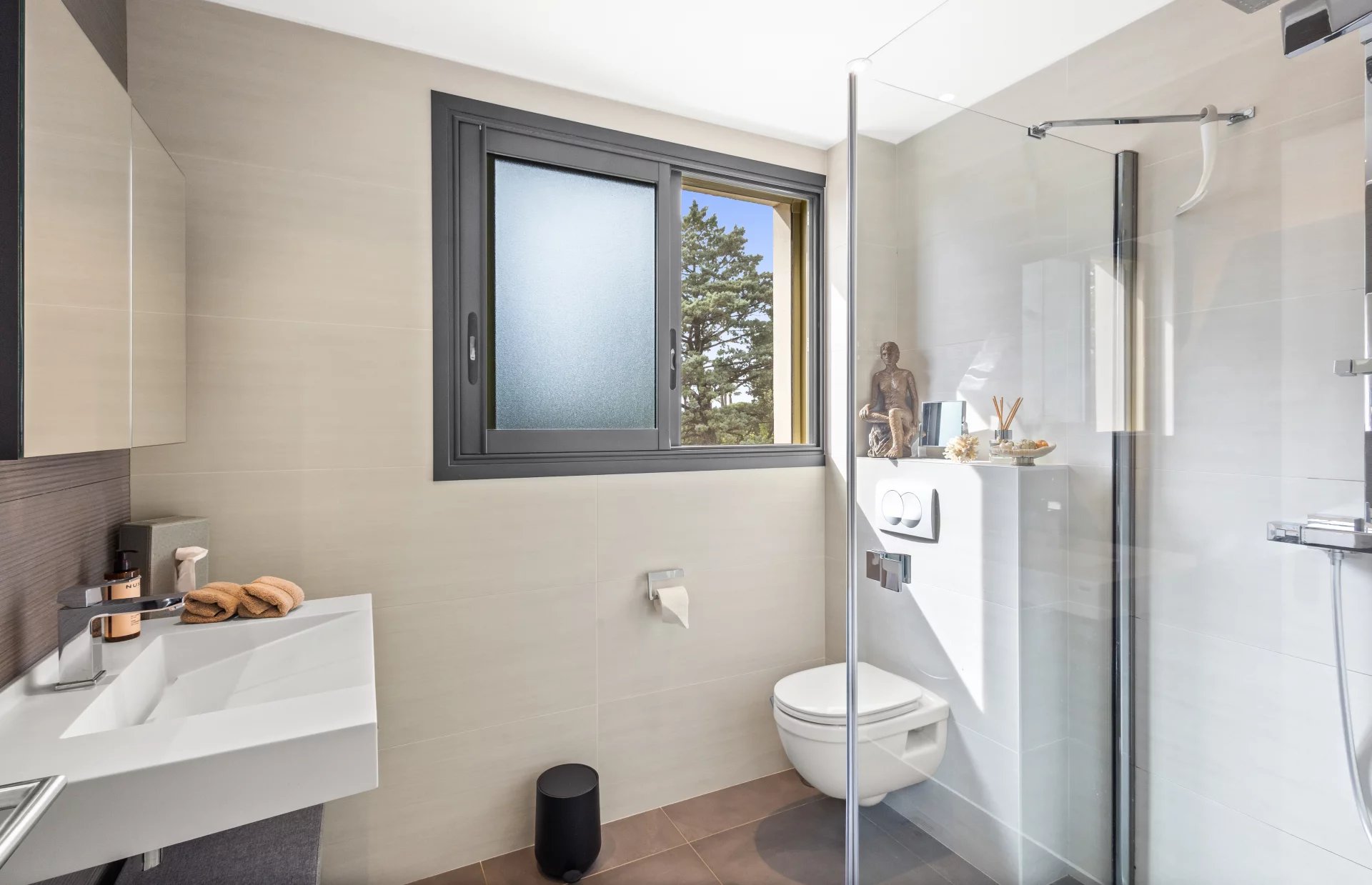 Renovated bathroom Modern bathroom with shower, sink and window, decorated with elegant accessories.