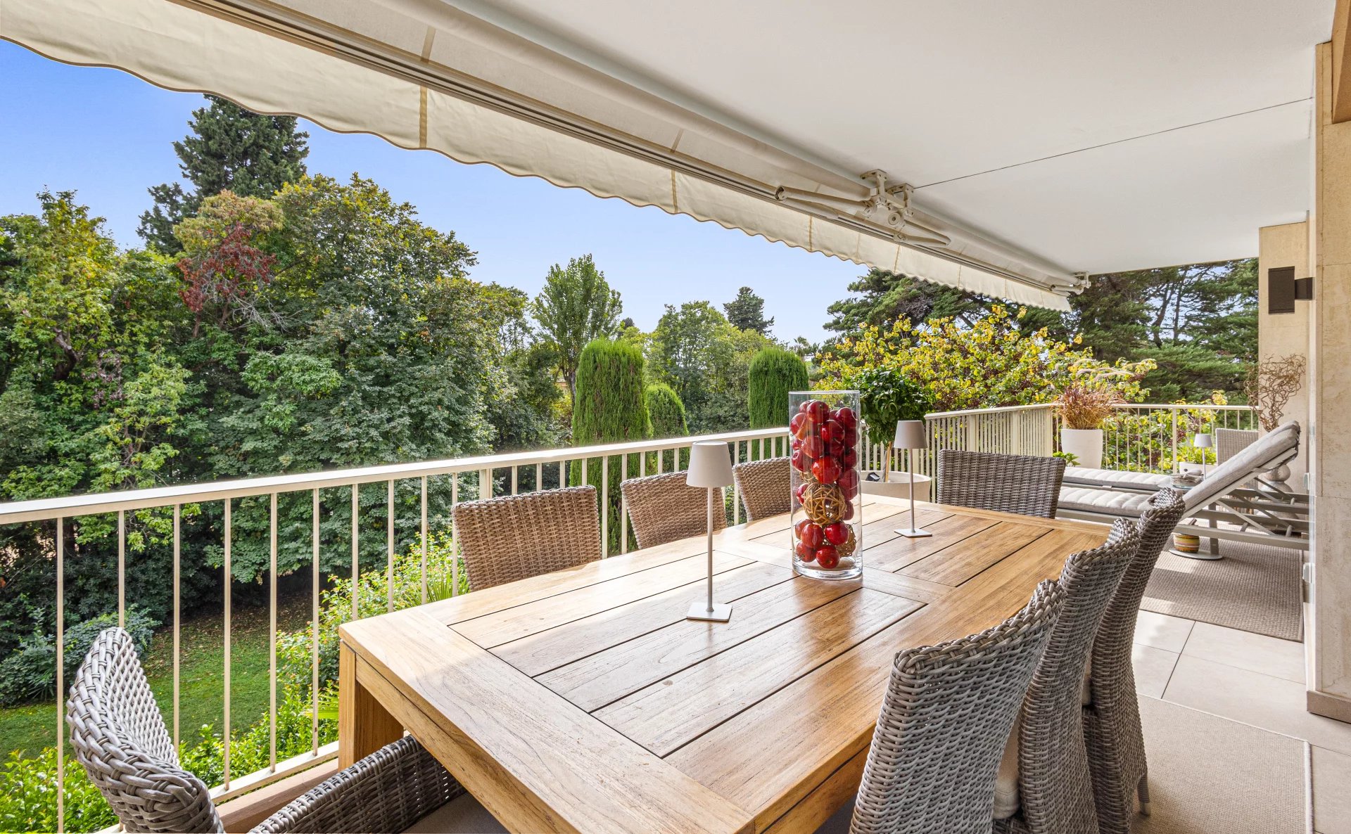 Terrace of a renovated apartment in Cannes Wooden terrace with table and chairs, overlooking a green park in Cannes.
