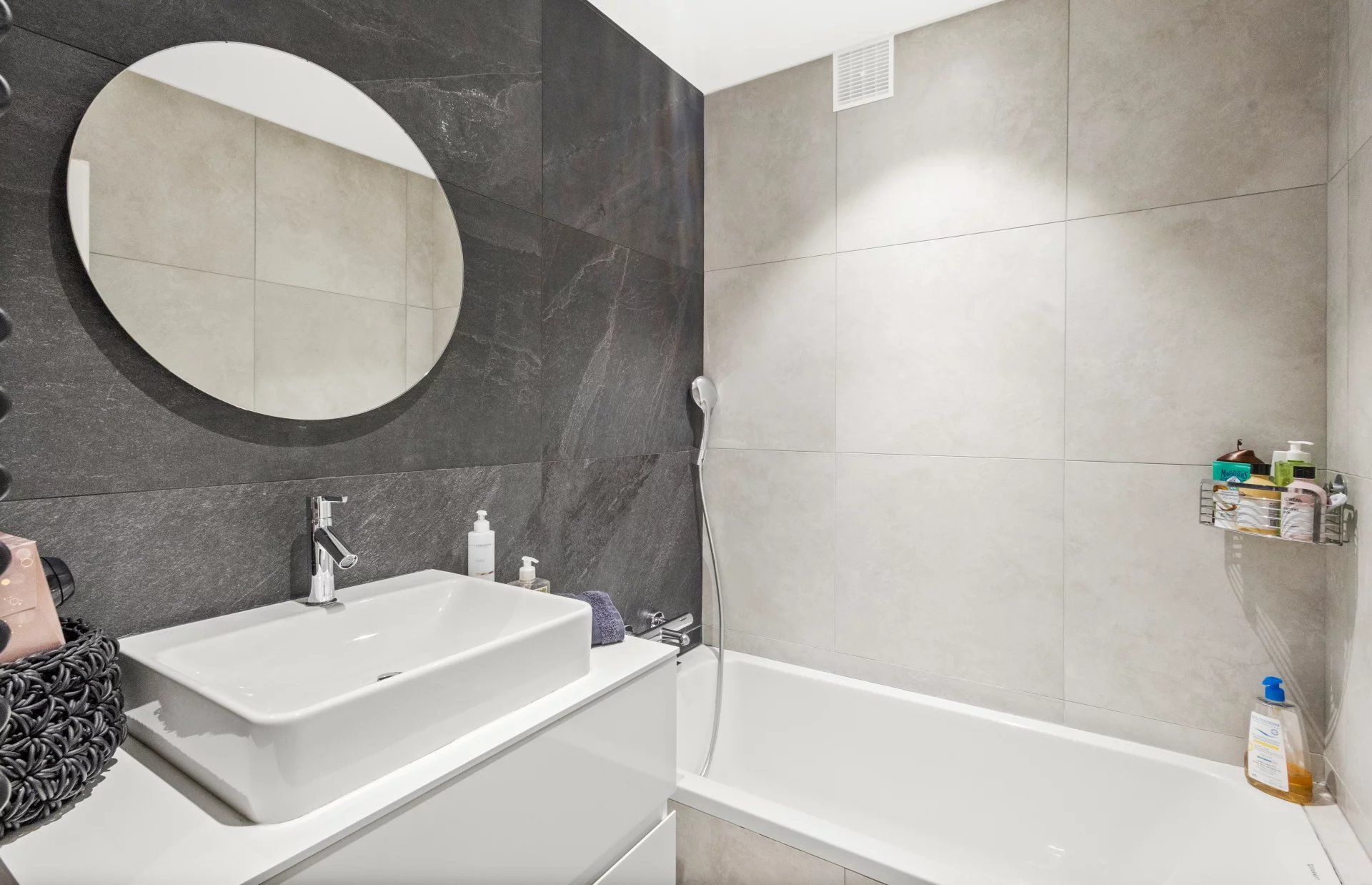 Renovated bathroom Modern bathroom with bathtub, sink and round mirror.