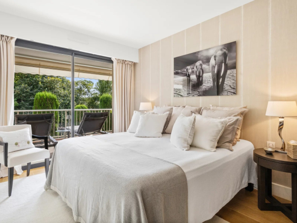 Room in a renovated apartment with double bed and access to a balcony, overlooking greenery.